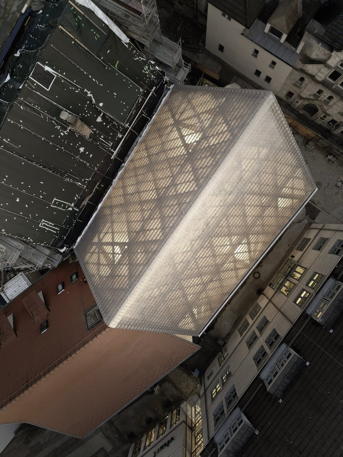 Vogelperspektive auf das Museum bei Dämmerung, ein leuchtender, halbtransparenter Baukörper inmitten dichter Altstadtbebauung © Brigida González